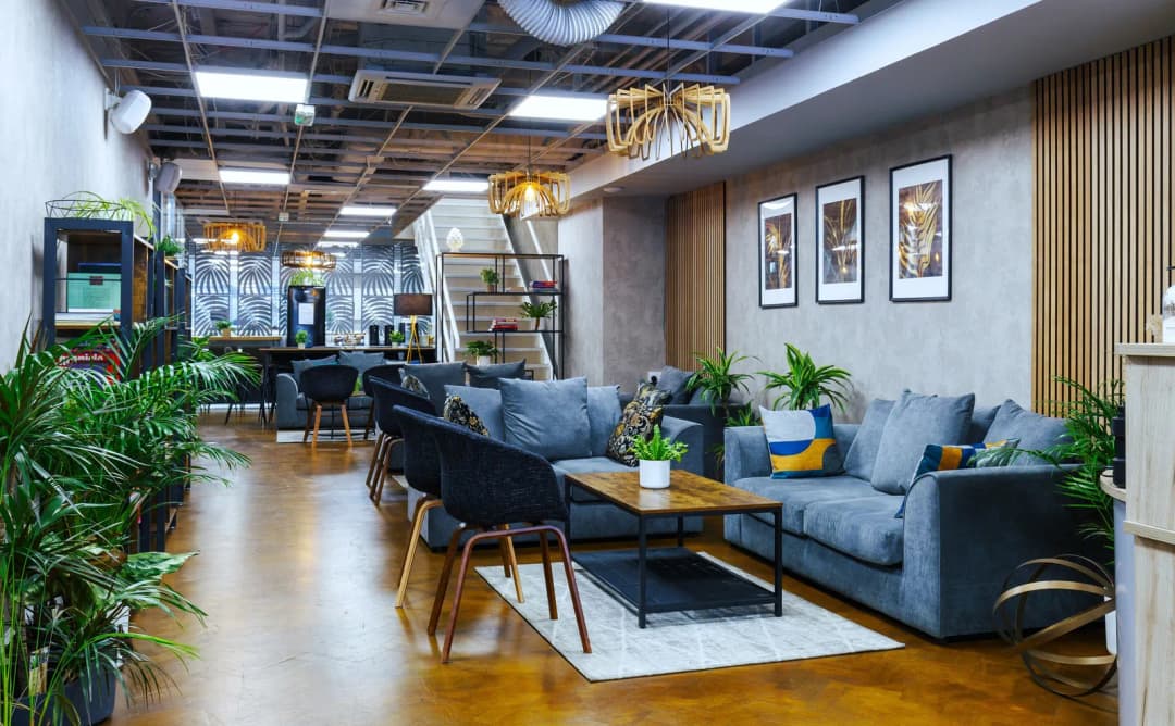 Lounge area of a flexible office centre with sofas, plants and a meeting table
